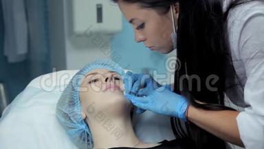在美容院，医生-美容师把肉毒杆菌注射到女孩`嘴唇上。 隆唇过程